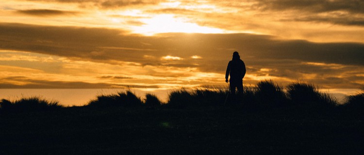 man standing on UK hill at sunrise