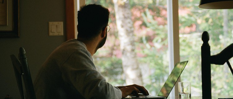 man working on a laptop indoors looking out of the window