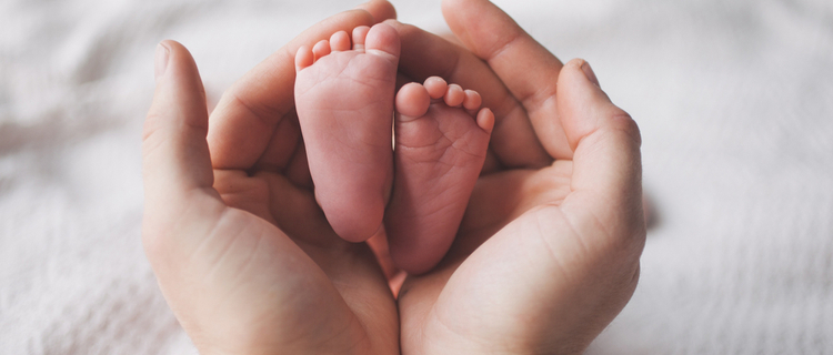 parent holding the feet of a newborn baby