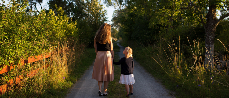 a parent and child walking down a country lane