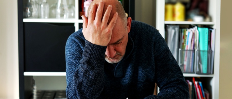 A man looks at receipts and holds his head in his hands.