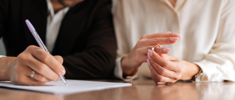 A man signing a document as a woman removes her ring