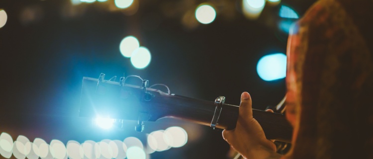 A guitarist playing on a brightly lit stage.