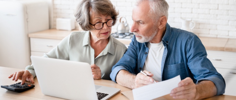 An older couple looking at a computer and a document.