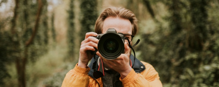 A person taking a photo in a forest.