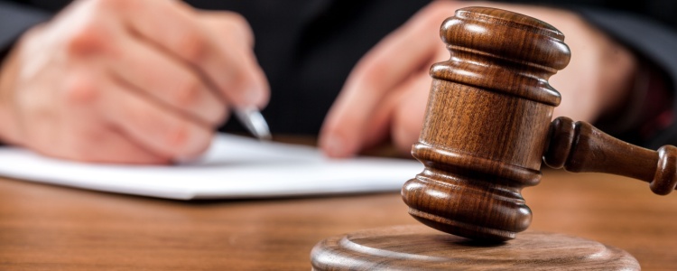A man with a gavel on his desk signing paperwork