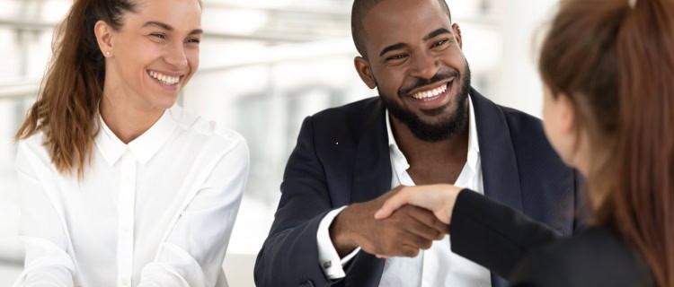 A couple shaking hands with a financial planner.