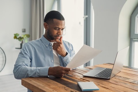 A man looking at paperwork deep in thought.